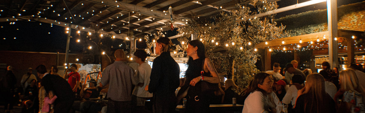 People chatting beneath festoon lights in a covered outdoor space
